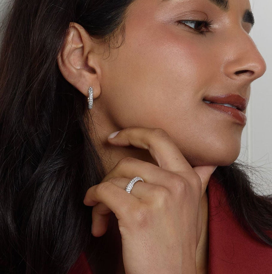 Woman in a red coat leaning against a white paneled wall.