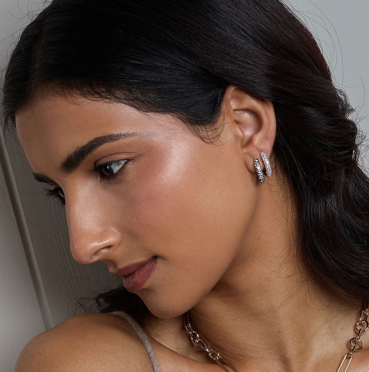 Woman wearing jewelry including a necklace, bracelet, and ring against a neutral background
