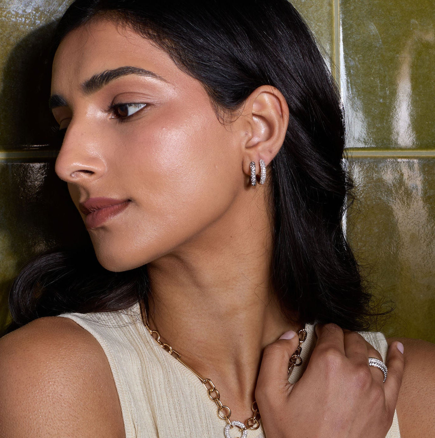 Woman wearing jewelry against a tiled wall